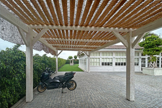Pérgola de madera con cubierta de lisyones y red de fibra vegetal para aparcamiento privado